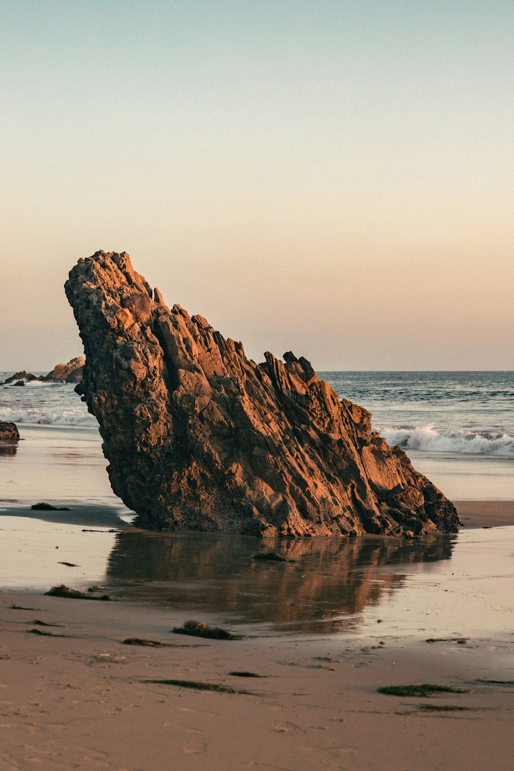 una gran roca sentada en la cima de una playa de arena