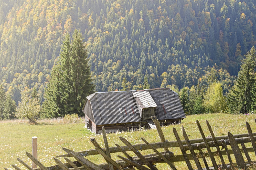 a barn in the middle of a field with trees in the background