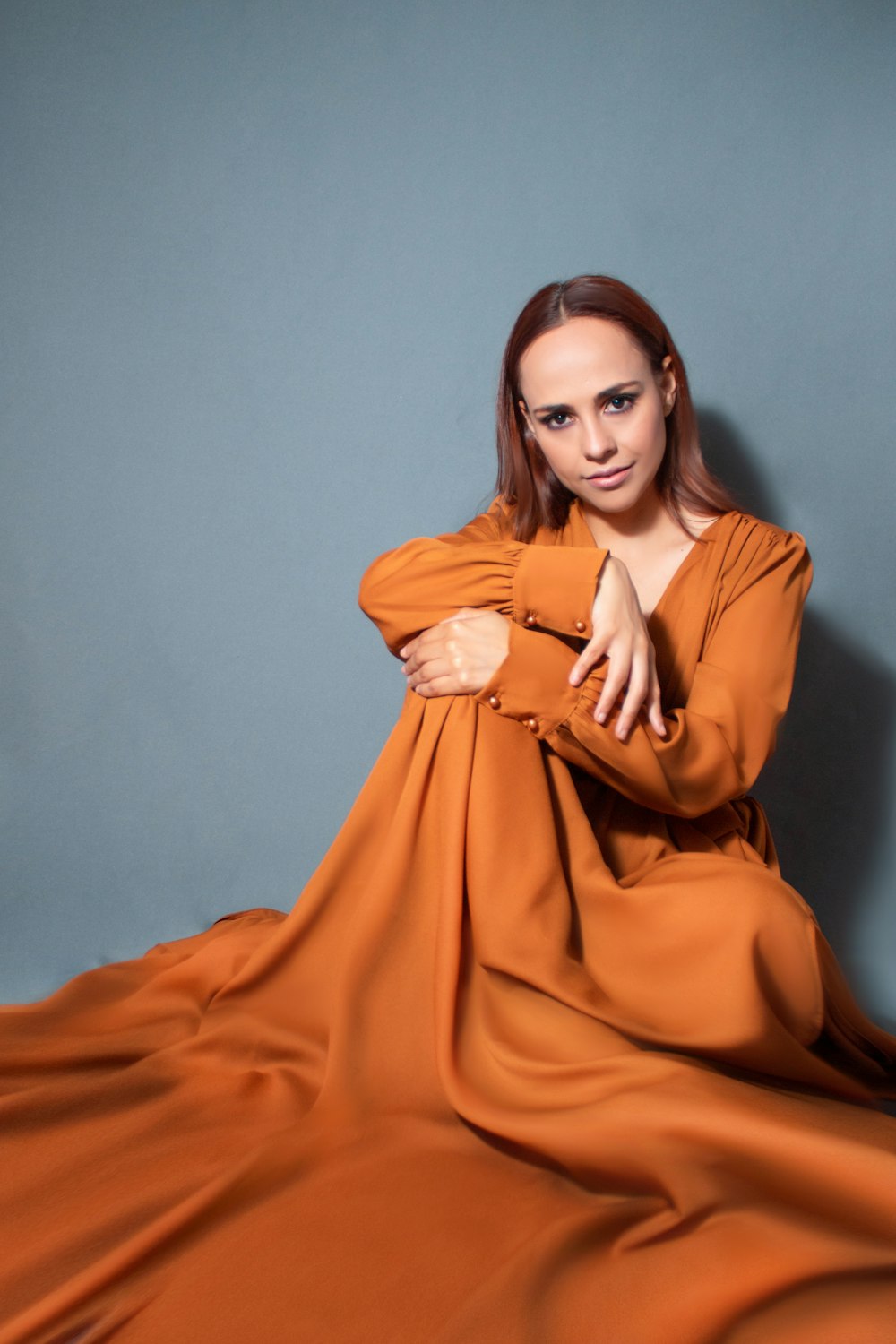 a woman in an orange dress posing for a picture