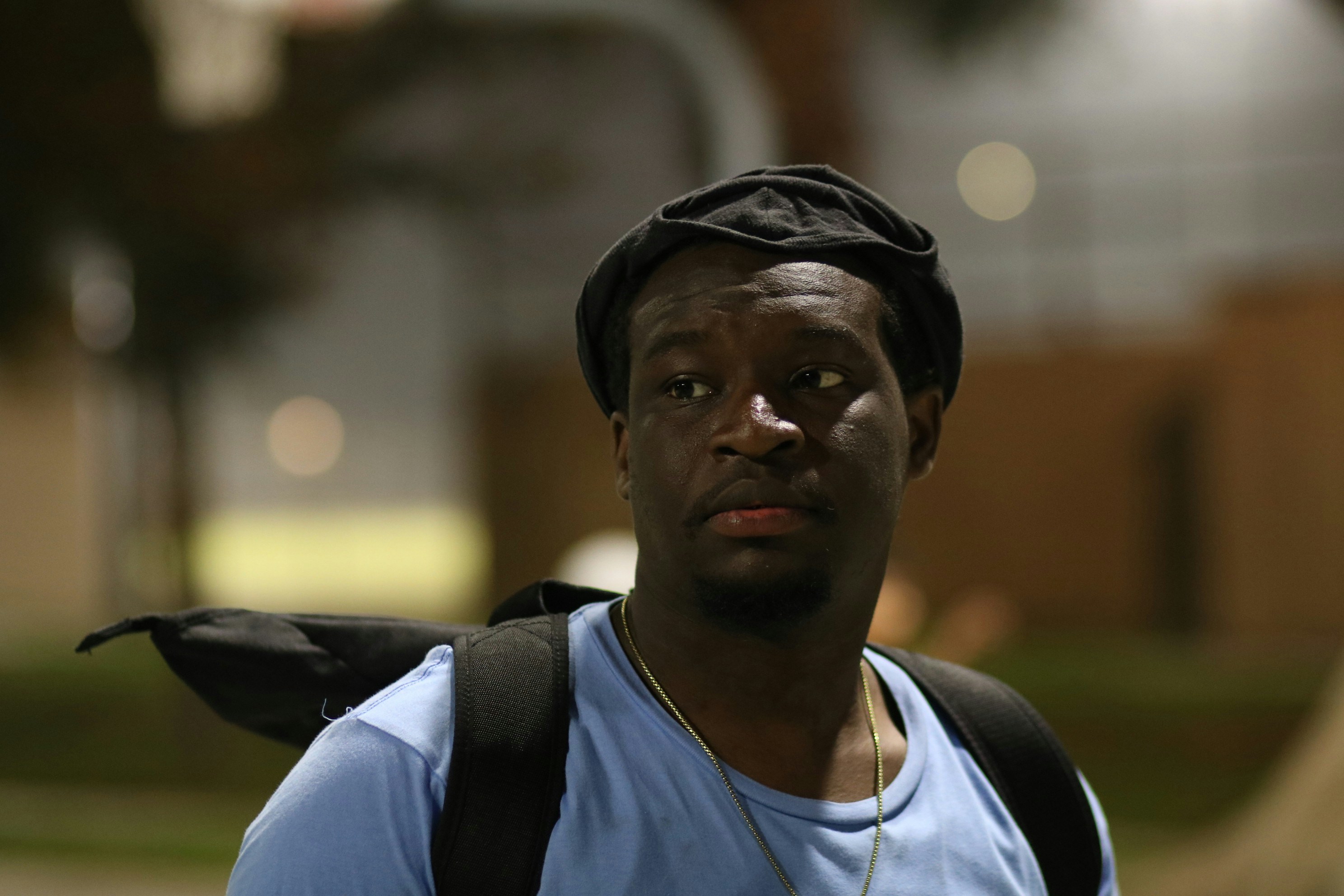 a black man with a blue shirt and a black backpack