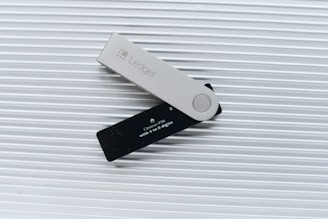 A user holding a Ledger device with the Ledger Live app open on a laptop in a cozy home office.