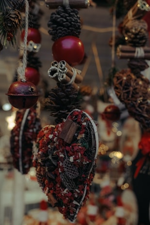 Festive hanging decorations featuring pinecones, red ornaments, cinnamon sticks, and heart-shaped arrangements with red and brown dried flowers.