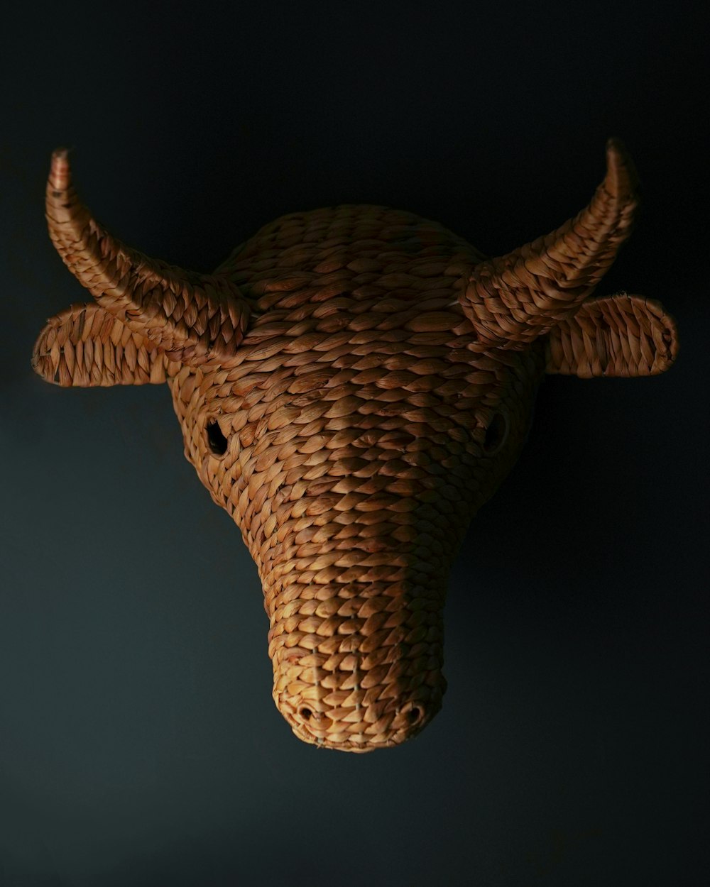 a woven cow's head hanging on a wall