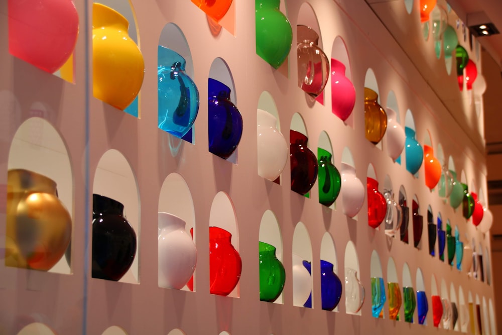 a wall with many different colored vases on it