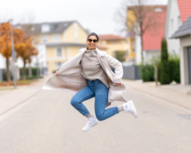a woman jumping in the air in the middle of a street