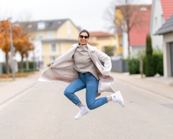 a woman jumping in the air in the middle of a street