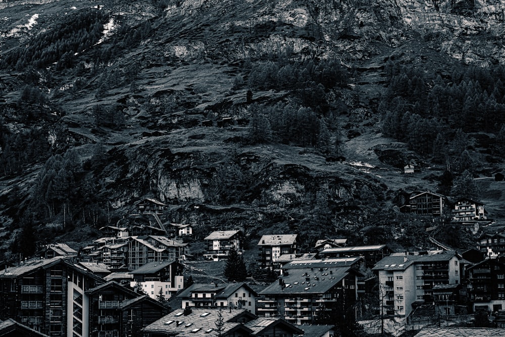 a black and white photo of a city below a mountain