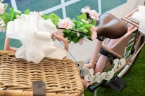 A vintage bicycle decorated with pastel flowers parked near a rustic wooden fence in a sunny meadow.