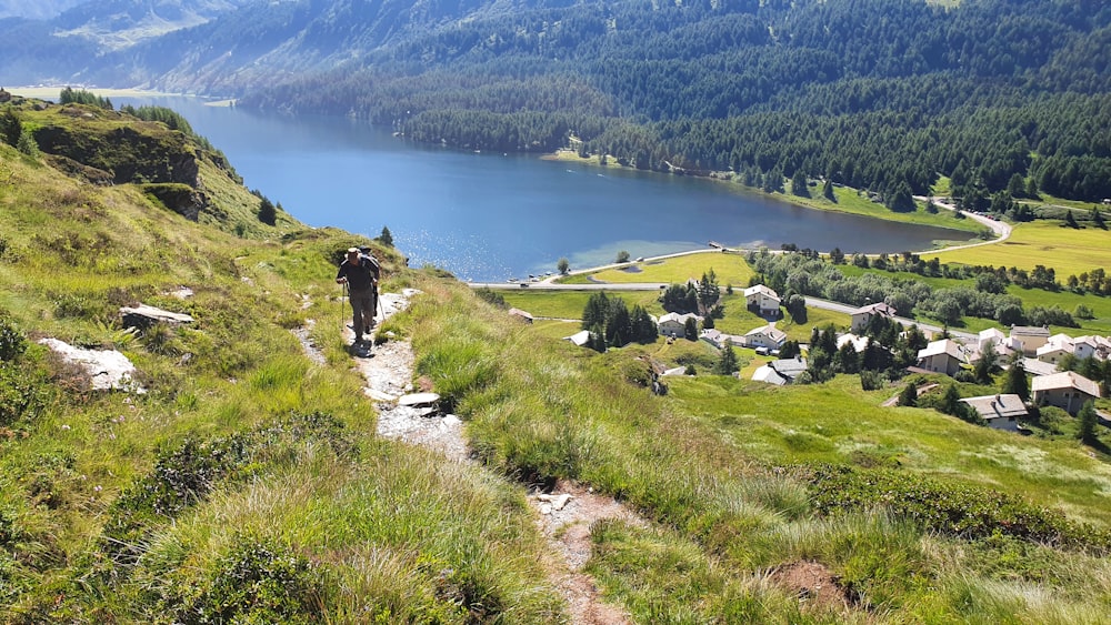 a man hiking up a hill with a lake in the background