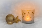 a candle and a star decoration on a snowy surface