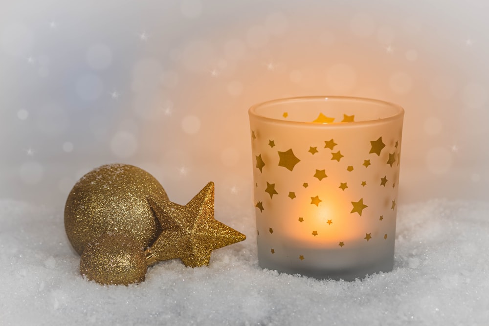 una vela y una decoración de estrellas sobre una superficie nevada