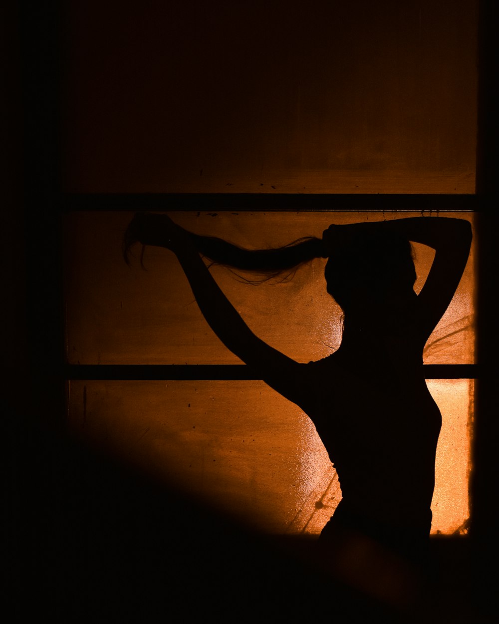 a silhouette of a woman with her hair blowing in the wind