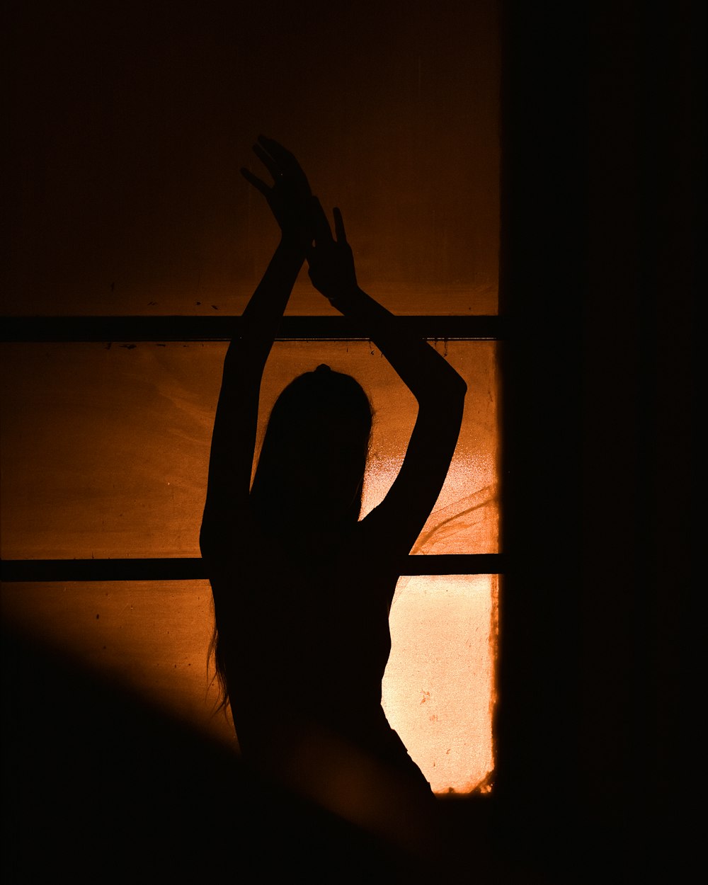 a woman standing in front of a window in the dark