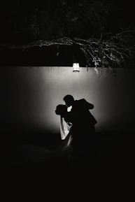 A couple sharing a quiet moment under soft pink and deep red hues.