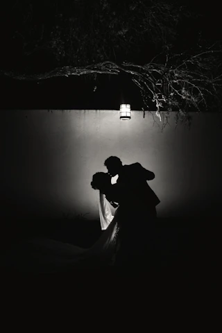 A couple sharing a quiet moment under soft pink and deep red hues.