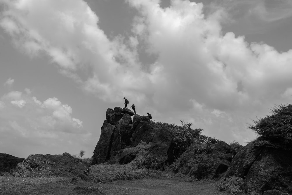 a black and white photo of some people on a rock