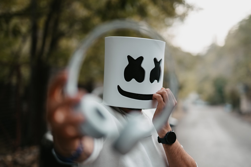 a person holding a coffee mug with a face drawn on it