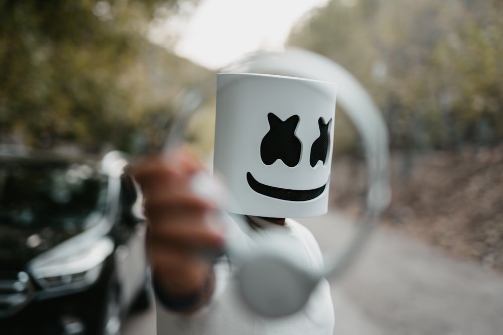 a person holding a coffee mug with a face drawn on it