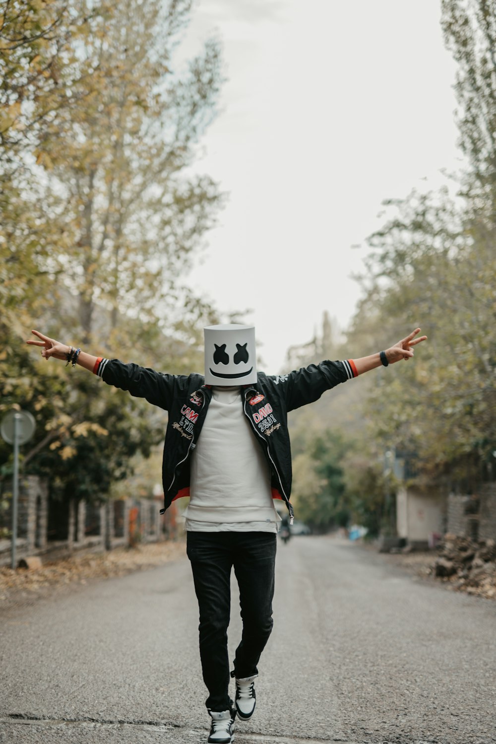 a man with his arms outstretched walking down a street