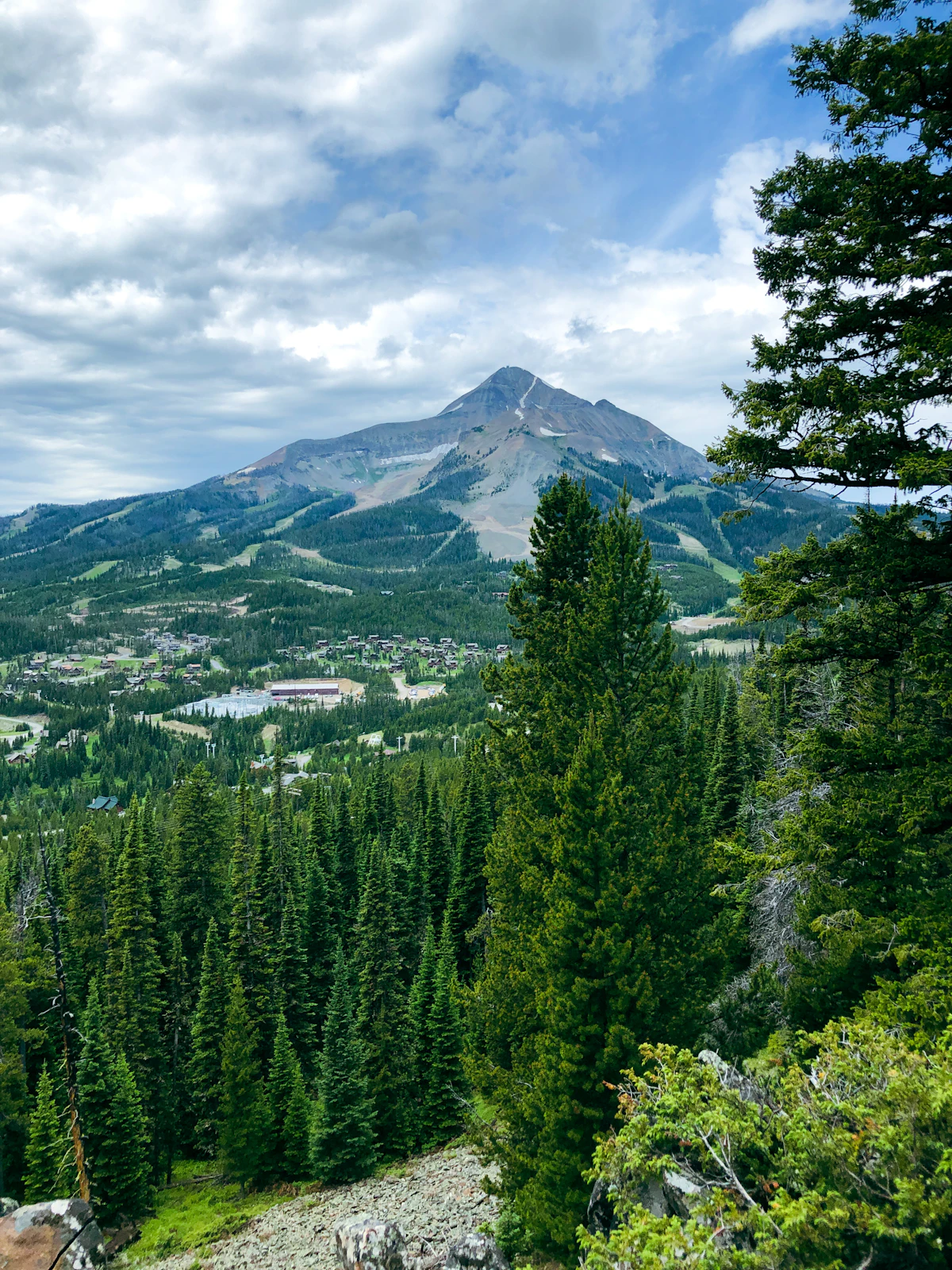 Lone Peak above the forest and the resort village at Big Sky, seen from a rocky slope among pines