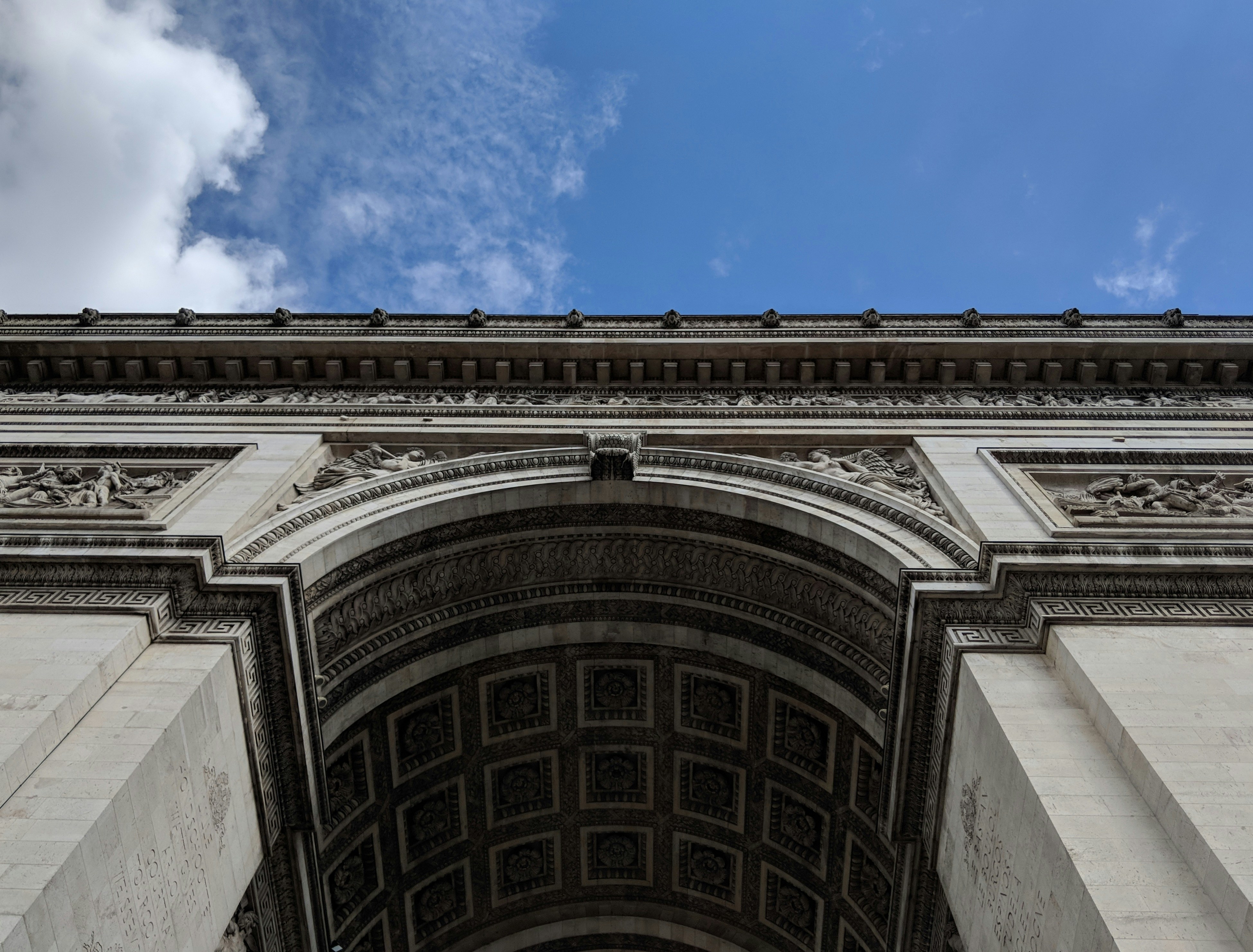 a very tall building with a sky in the background, The Arc de Triomphe cuts across the sky.