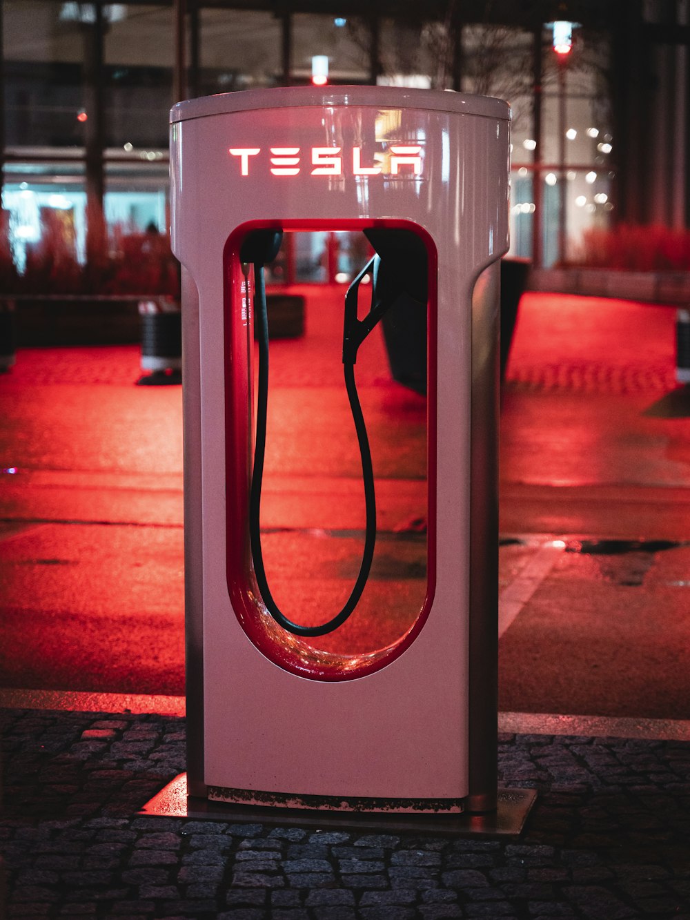 a red and white phone booth sitting on the side of a road