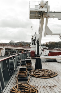 a boat deck with ropes on it and a crane in the background