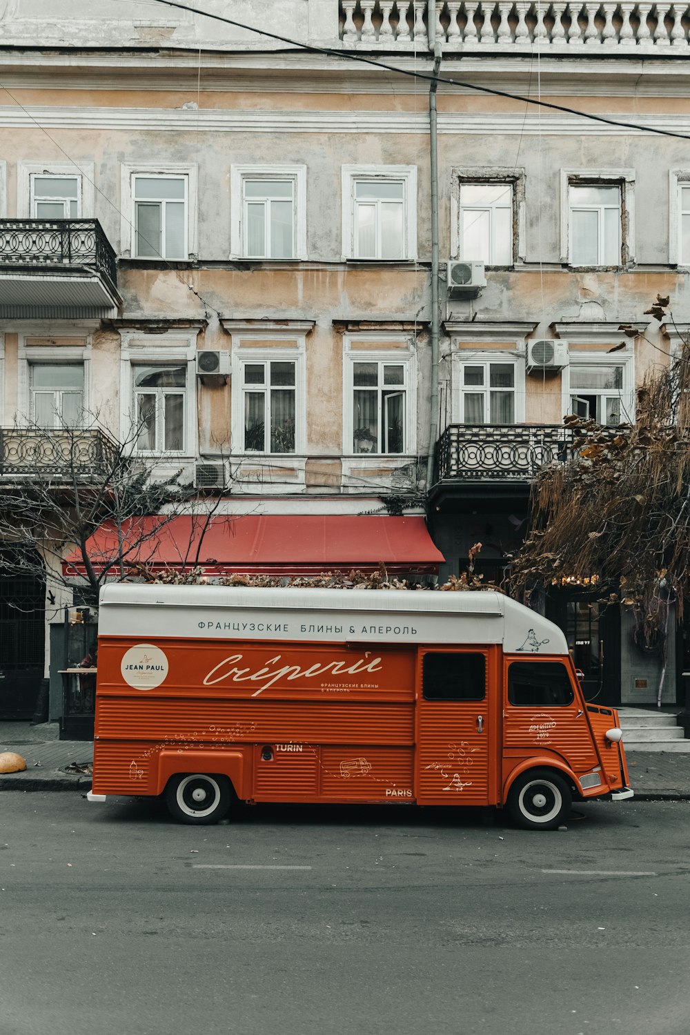 an orange and white food truck parked in front of a building