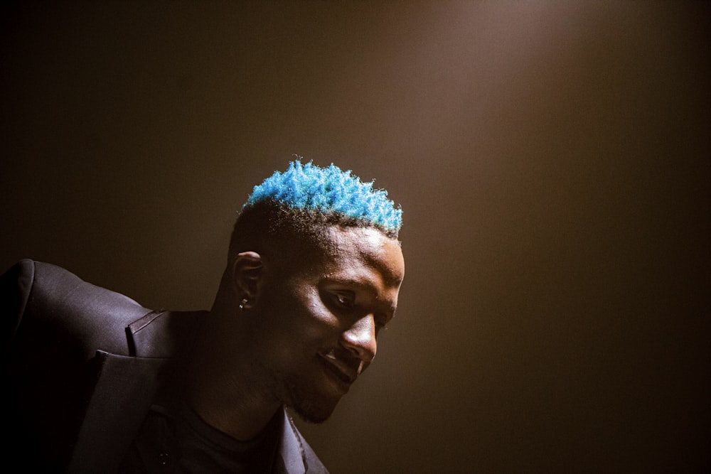 a man with a blue mohawk in a dark room