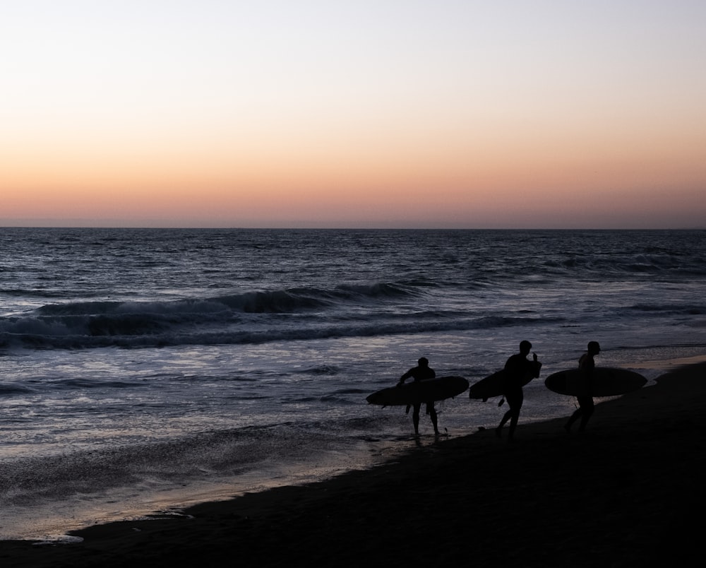 a group of people carrying surfboards on top of a beach