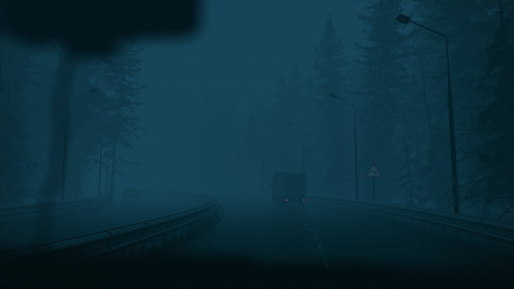 a truck driving down a foggy road at night