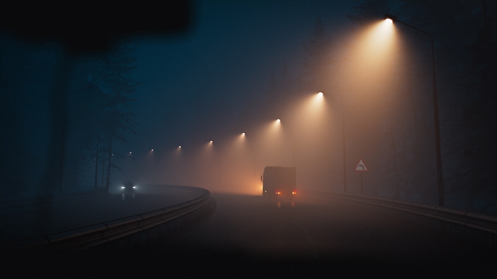 a truck driving down a foggy road at night