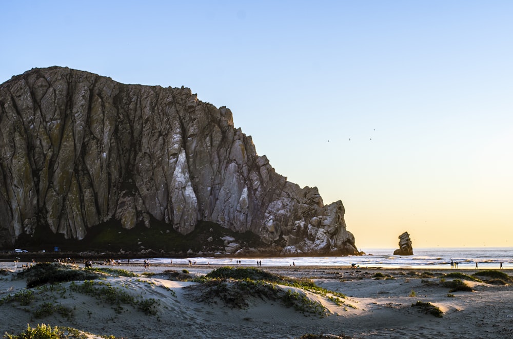 a beach with a large rock formation in the background