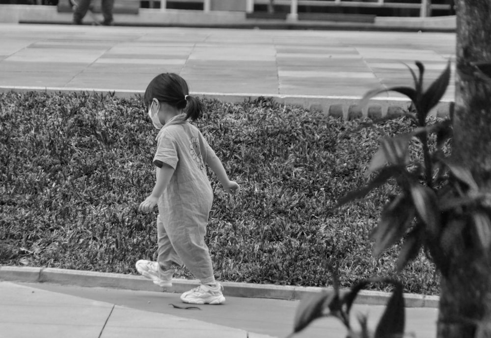 a little girl that is walking down a sidewalk