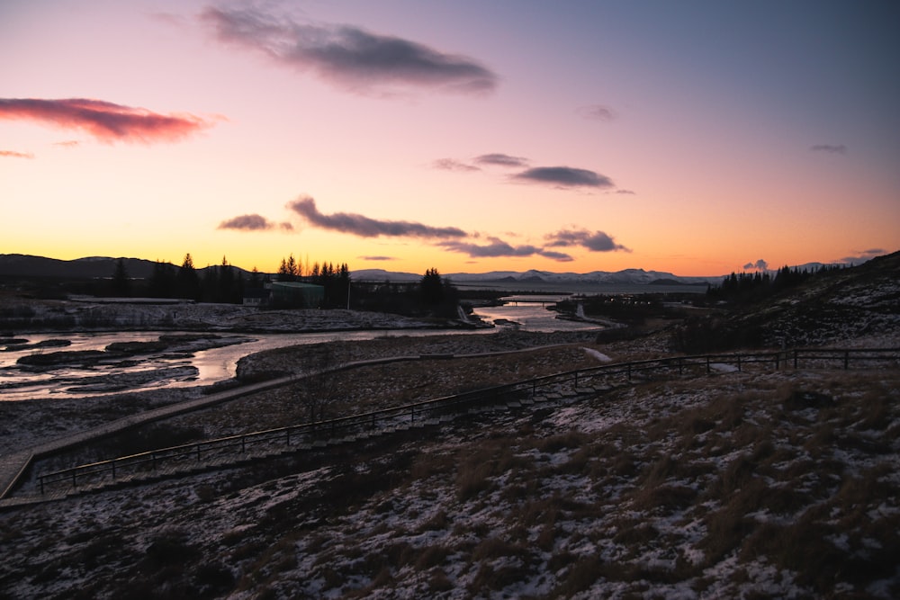 the sun is setting over a river in the mountains