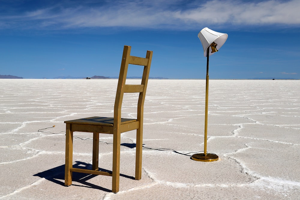 a chair and a lamp in the middle of a desert