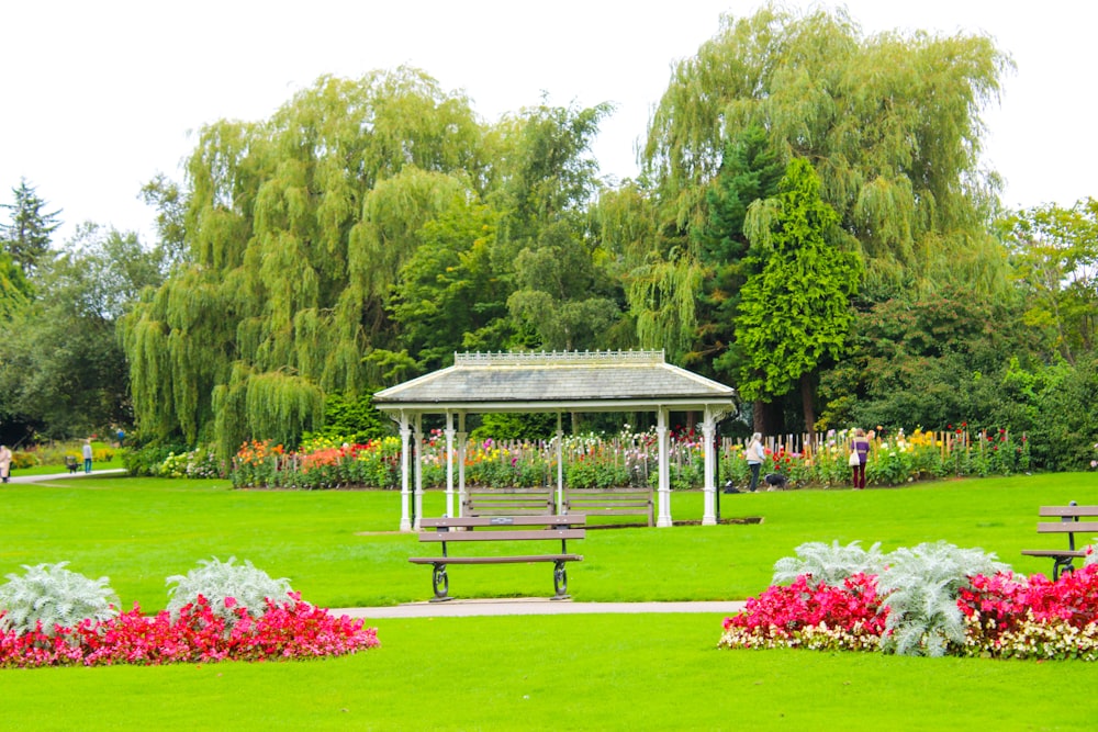 a park with a gazebo and flowers in the foreground