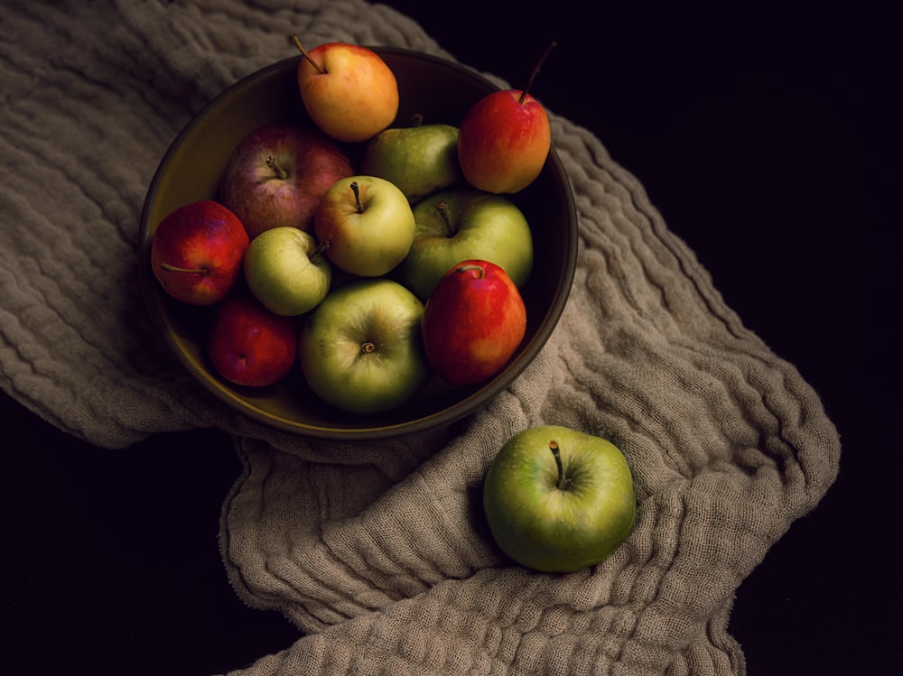 a bowl of apples sitting on top of a towel