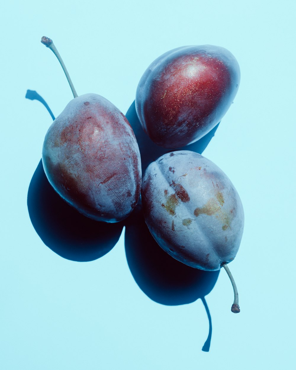 three plums sitting on top of each other
