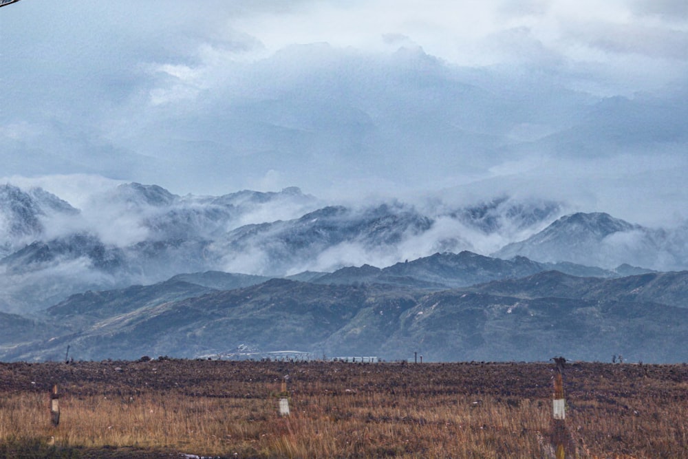 a plane flying over a field with mountains in the background