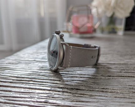 Close-up of a sleek analog wristwatch with a leather strap resting on a wooden table