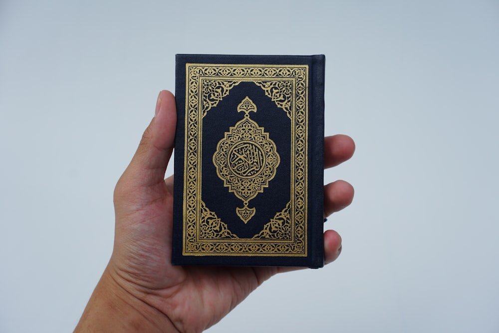 a hand holding a black and gold playing card