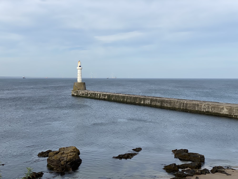 a light house sitting on top of a pier next to the ocean