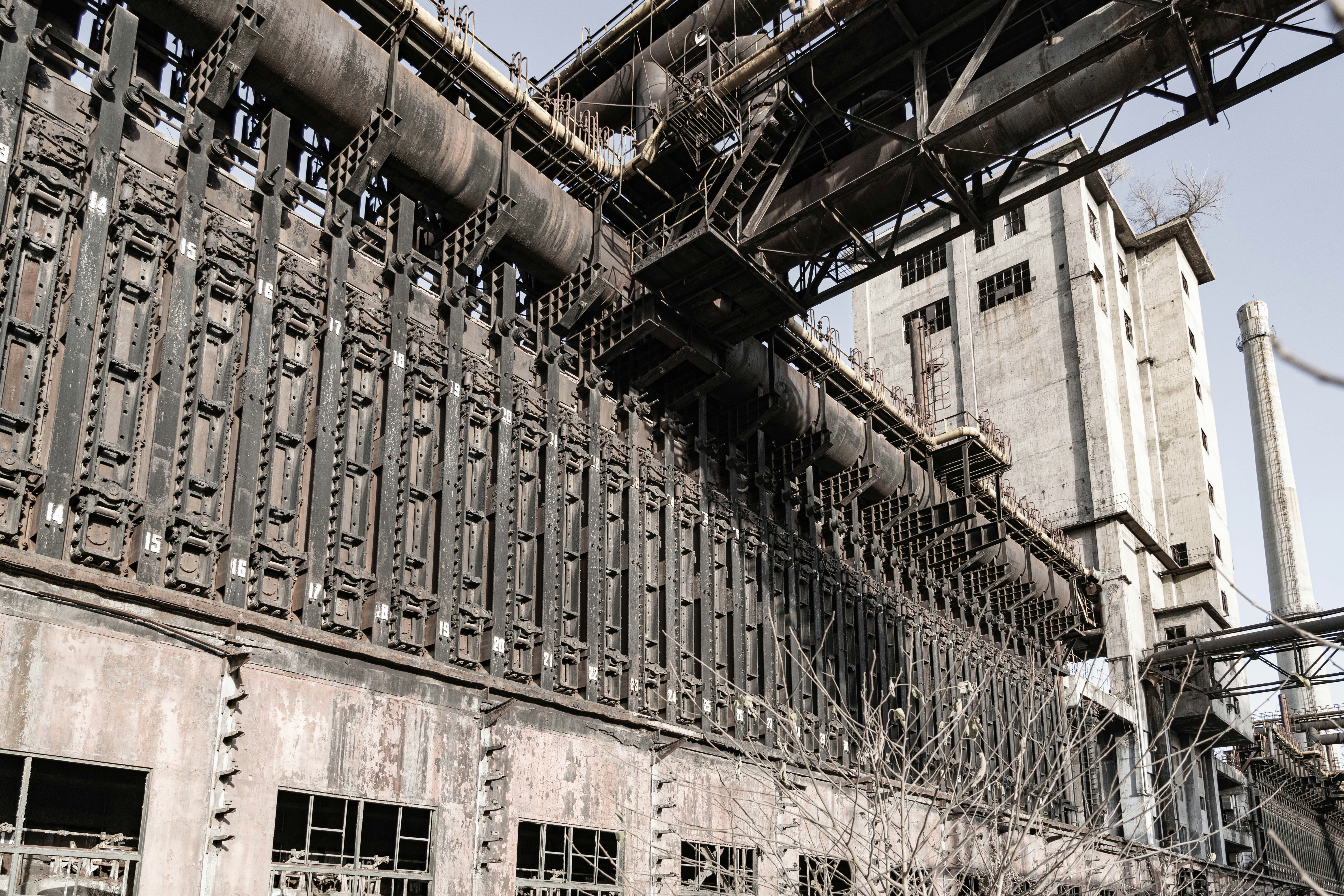 Dark abandoned industrial building exterior at night, dim orange security lighting, heavy shadows