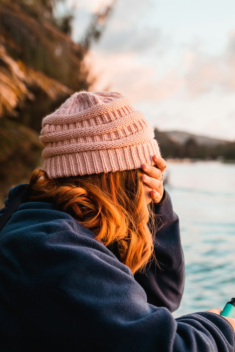 a woman in a pink hat is looking at her cell phone