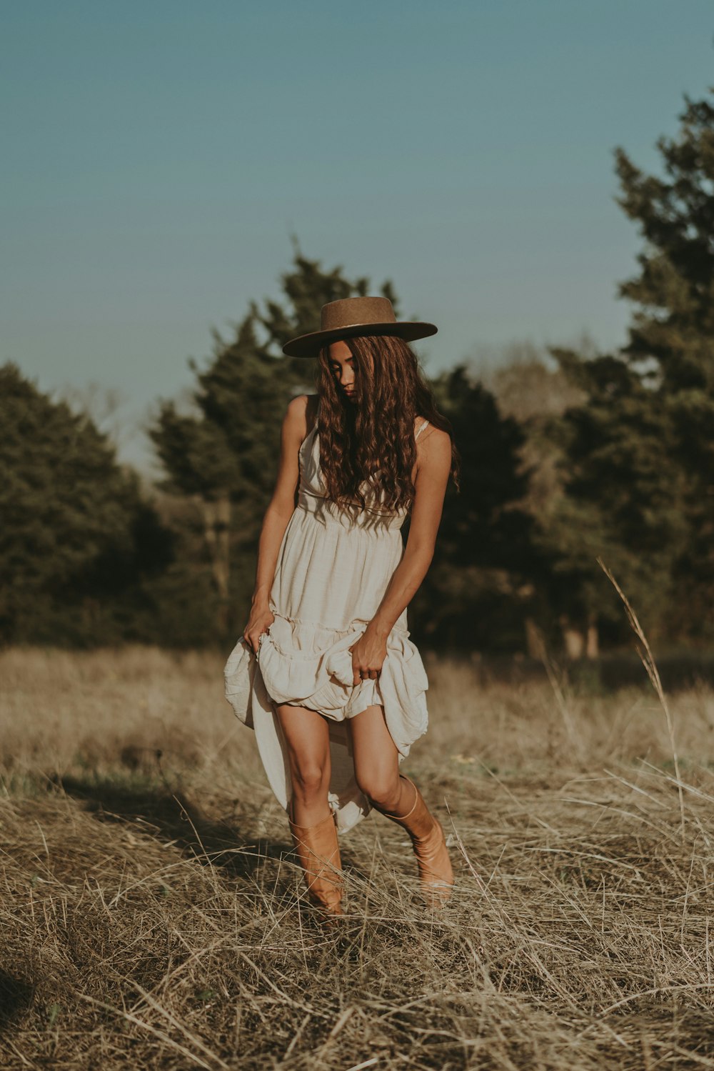 a woman in a hat walking through a field