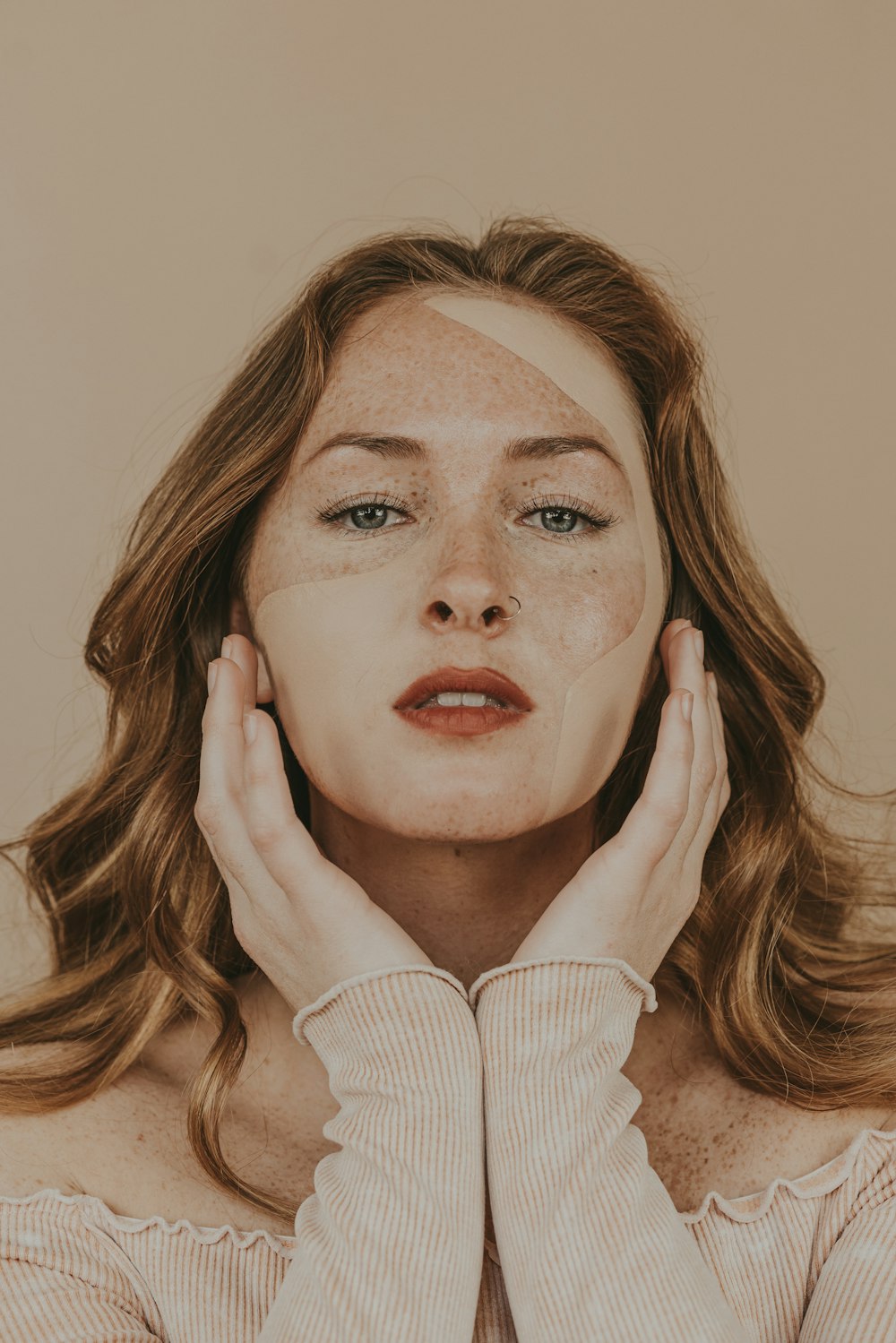 Una donna con le lentiggini sul viso che tiene le mani al viso