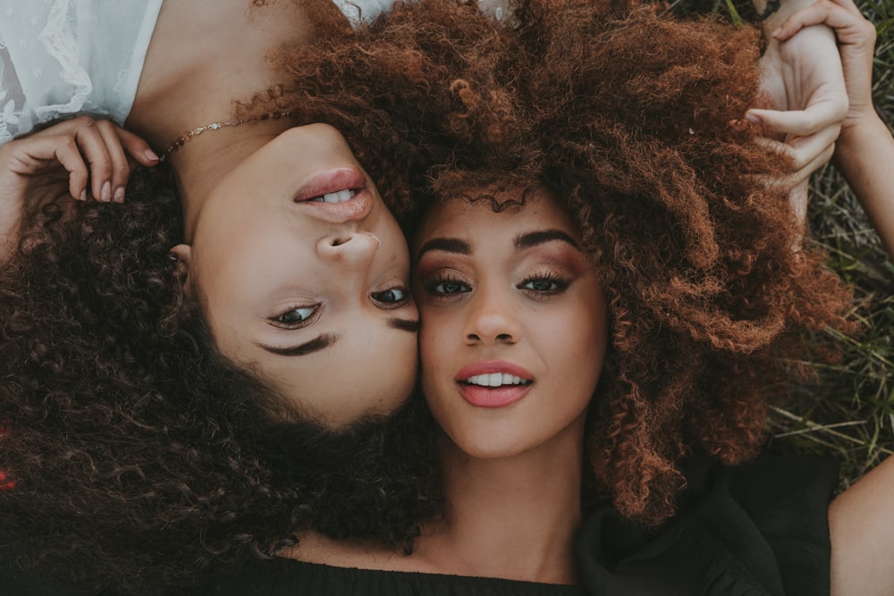 two women laying on the ground with their heads on each other