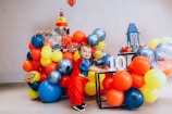 a young boy sitting at a table surrounded by balloons