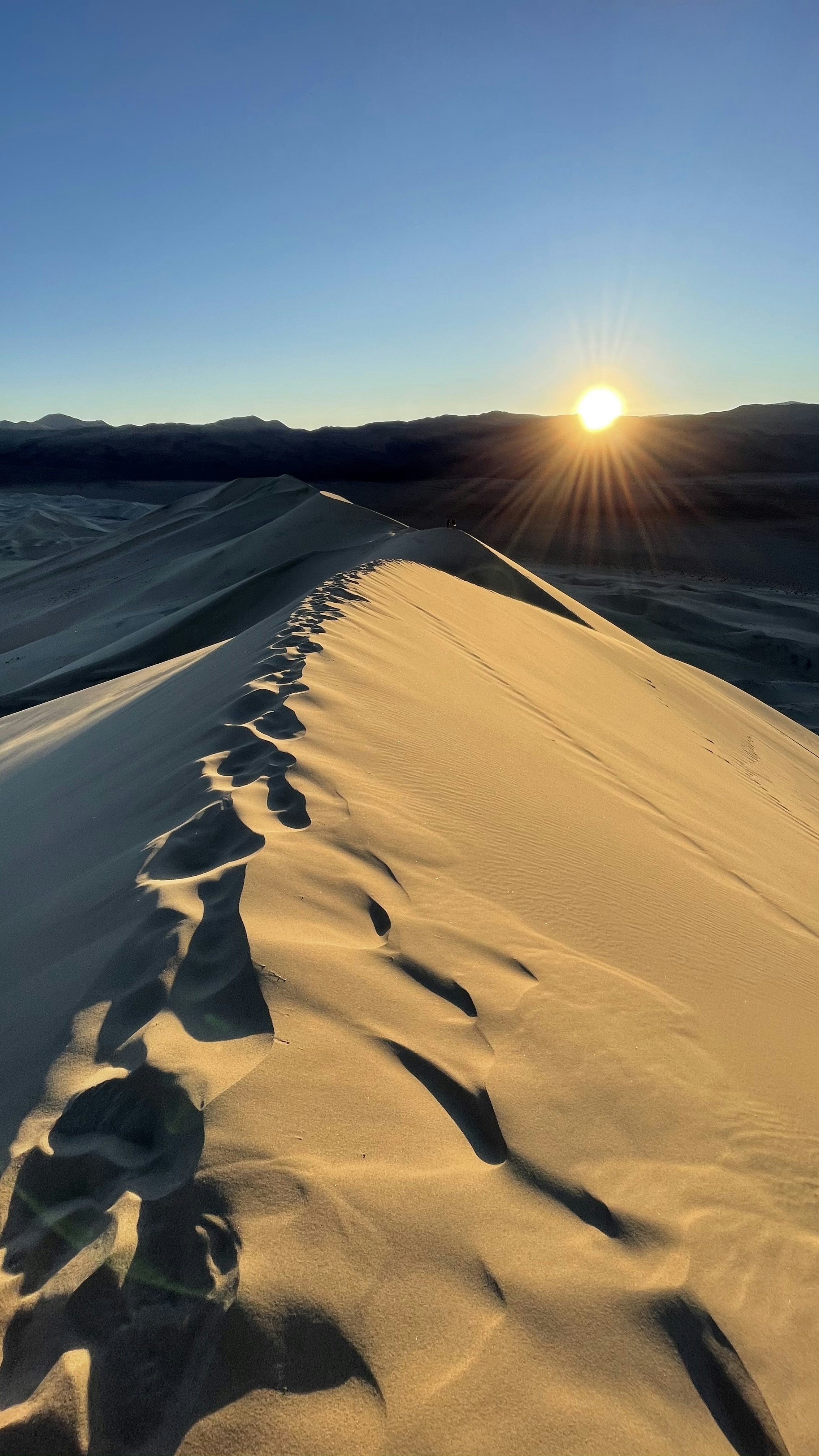 the sun is setting over the sand dunes